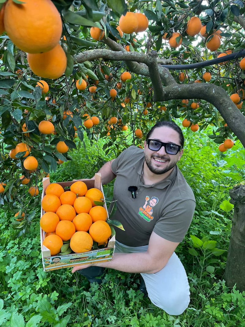 Giancarlo hält eine Kiste Orangen 